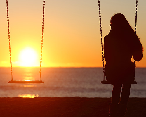 Single woman alone swinging on the beach
