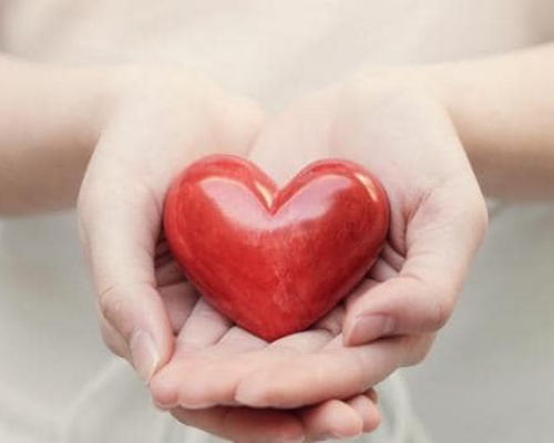 A hand holding a heart shaped apple